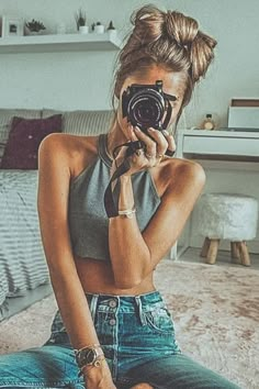 a woman sitting on the floor taking a photo with her camera in front of her