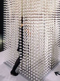 a woman is standing in front of a sculpture made out of balls and stringing