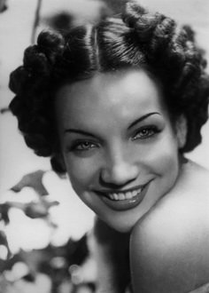 an old black and white photo of a woman smiling