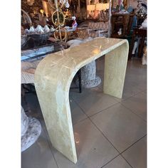 a marble bench sitting on top of a tile floor next to a table with a chandelier in the background