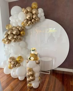 balloons and cake on display in front of a wall with white and gold decorations at a wedding reception