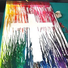 the cross is painted in rainbow colors with crayons and paintbrushes next to it