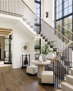 a white staircase with black railing and wooden flooring next to a glass doored entryway