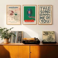 there are three posters on the wall above a record player and a potted plant