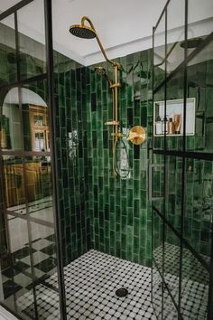 a bathroom with green tiled walls and flooring, shower head and hand held faucet