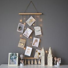 a white table topped with pictures and lights next to a wall mounted photo frame on a gray wall