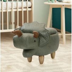 an elephant shaped chair sitting on top of a wooden floor next to a baby crib