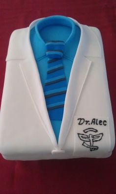 a white jacket with a blue striped tie and dr alec logo on the collar