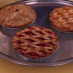 three pies sitting on top of a metal tray next to a person's hand