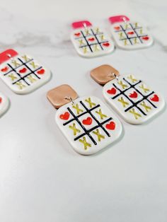 several white and red earrings with gold accents on a marble counter top next to each other