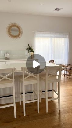 a kitchen table with four chairs and a counter top in front of a large window