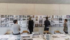 people standing around a table with pictures on the wall