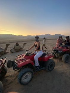 people riding four wheelers in the desert at sunset