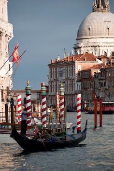 a gondola in the middle of a canal with buildings on both sides and a dome