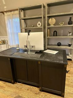 a desk with a computer on top of it in front of some bookshelves