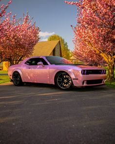 a pink car parked in front of some trees