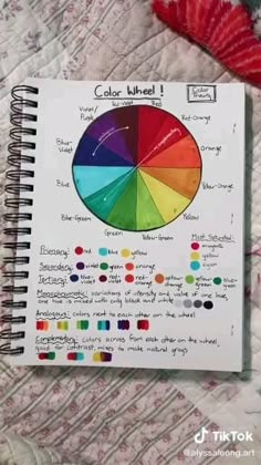 a spiral notebook with a color wheel on top of the page is open to show it's contents