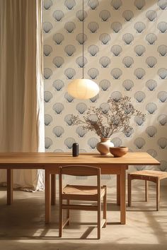 a dining table with two chairs and a vase on it in front of a wallpapered background