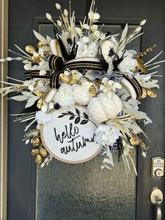 a wreath with white flowers and gold leaves is hanging on the front door to say hello autumn