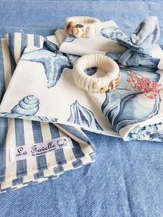 three napkins with seashell designs on them are sitting on a blue table cloth