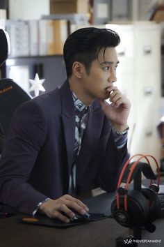 a man in a suit and tie sitting at a desk with his hand on his chin