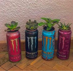 three monster cans with plants in them sitting on the floor next to a white wall