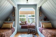 two beds in a small room with wooden floors and white walls, one has a rocking chair next to the window