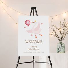 a welcome sign for a baby shower is displayed on an easel with lights in the background