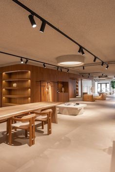 an empty room with tables and benches in the center is lit by spotlights from overhead lights