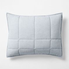 a light blue pillow on a white background with an embroidered square pattern in the middle