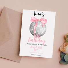 a birthday party card with a pink bow and disco ball on it next to an envelope