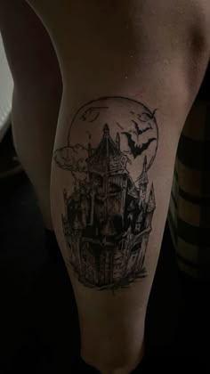 a woman's leg with a black and white tattoo design on her thigh that has an image of a castle in the background