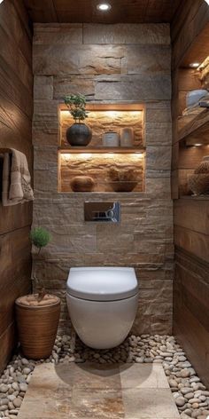 a toilet sitting in the middle of a bathroom next to a stone wall and floor