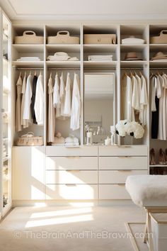 a large white closet with lots of drawers and clothes hanging on the shelves, along with shoes