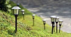 some lights that are on the side of a grass covered hill in front of a road