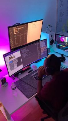 a man sitting in front of two computer monitors