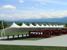 several red buses parked in front of a white tent