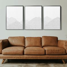 two brown leather couches sitting next to each other in front of a white wall