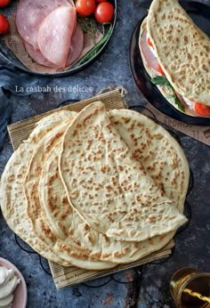 several pita breads on plates with tomatoes and chicken