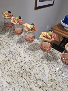 several wine glasses are lined up on a marble counter top, with appetizers in the middle