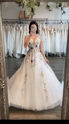 a woman taking a selfie in front of a mirror wearing a wedding dress with flowers on it