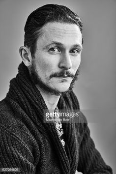 an old photo of a man with long hair and a beard wearing a knitted scarf