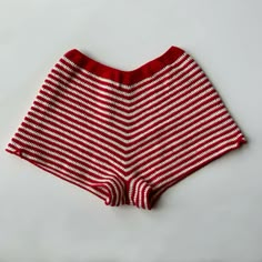 a red and white striped shorts on a white surface with the bottom half rolled up