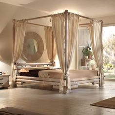 a canopy bed with curtains on the sides and pillows on the bottom, in a bedroom