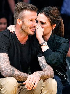 a man and woman sitting next to each other in front of a crowd with tattoos on their arms