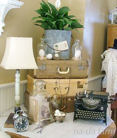 a pile of luggage sitting on top of a table next to a lamp and a potted plant