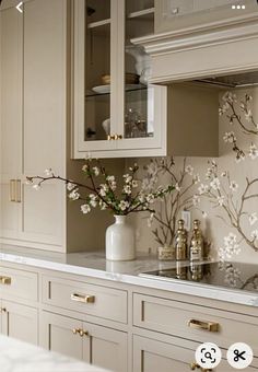 a kitchen with white cabinets and flowers on the counter