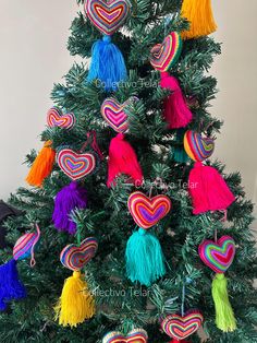 a small christmas tree decorated with multi colored tassels and heart shaped ornament ornaments