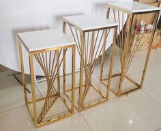 three gold and white side tables sitting on top of a floor next to each other