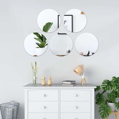 a white dresser topped with lots of mirrors next to a plant and potted plants